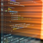 Close-up image of a computer screen displaying colorful programming code in a warm setting.